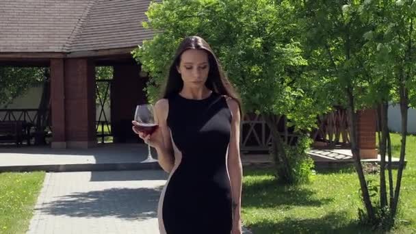 Elegáns nő üveg borral sétál a kastély kertjében — Stock videók
