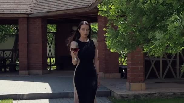 Elegante Frau mit einem Glas Wein im Garten des Herrenhauses — Stockvideo