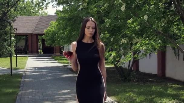 Elegant kvinna med glas vin promenader i trädgård herrgård — Stockvideo