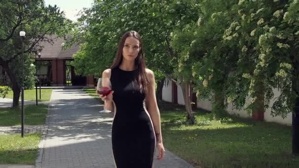 Elegante mujer con copa de vino caminando en jardín de mansión — Vídeos de Stock