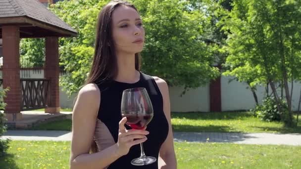 Mulher elegante com copo de vinho andando no jardim da mansão — Vídeo de Stock