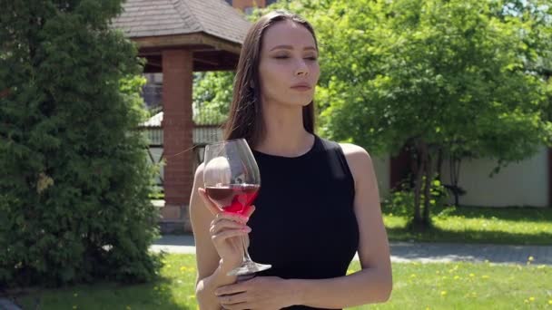Elegant kvinna med glas vin promenader i trädgård herrgård — Stockvideo