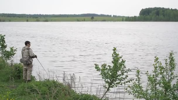 Rybak kręcący się na kołowrotku. Połowy na rzece letniej — Wideo stockowe