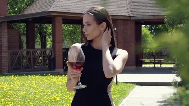 Elegante vrouw met glas wijn wandelen in de tuin van het herenhuis — Stockvideo