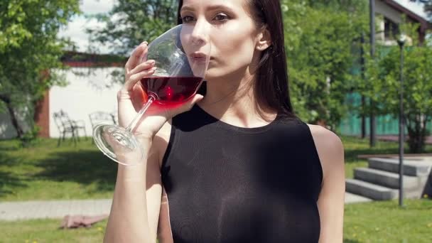 Elegant woman with glass of wine walking in garden of mansion — Stock Video