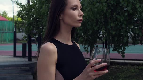 Elegant woman with glass of wine walking in garden of mansion — Stock Video