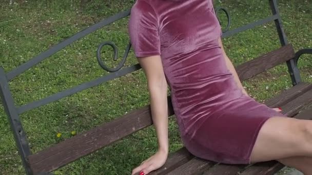 Elegante jonge brunette ontspannen op bank in park — Stockvideo