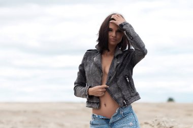 Kameraya bakan ve kırsalın bulanık arka planında kot ceketli çekici bir kadın model.