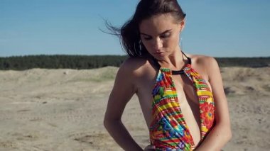 Mayo giymiş sıska bir kadın başka tarafa bakıyor.