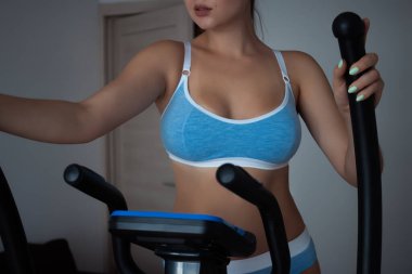 Antrenman sırasında evde stepper kullanan, iç çamaşırlı, tanınmayan baştan çıkarıcı bir kadından.