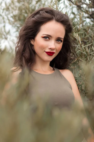 緑の庭に赤い唇と長い髪の木の近くに立って離れて見てケアフリースタイリッシュな女性 — ストック写真