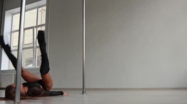 Stüdyoda direğin üstünde dans eden esnek bir kadın.