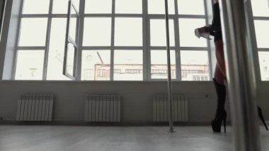 Stüdyoda direğin üstünde dans eden esnek bir kadın.