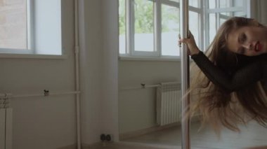 Stüdyoda direğin üstünde dans eden esnek bir kadın.