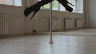 Stüdyoda direğin üstünde dans eden esnek bir kadın.