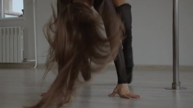 Stüdyoda direğin üstünde dans eden esnek bir kadın.