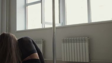 Stüdyoda direğin üstünde dans eden esnek bir kadın.