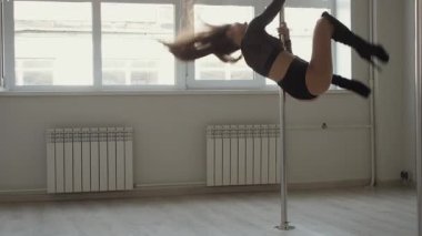 Stüdyoda direğin üstünde dans eden esnek bir kadın.