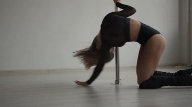 Stüdyoda direğin üstünde dans eden esnek bir kadın.