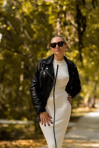 Slim Kobieta Modnej Białej Sukience Okulary Przeciwsłoneczne Zdjąć Skórzaną Kurtkę — Zdjęcie stockowe