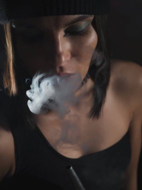 Şapkalı çekici bir kadın evde dinlenirken nargile tüttürüyor.