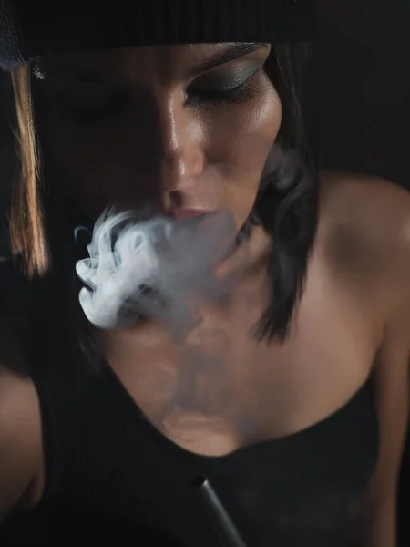 Mulher Atraente Chapéu Exalando Fumaça Narguilé Enquanto Descansa Quarto Escuro — Fotografia de Stock