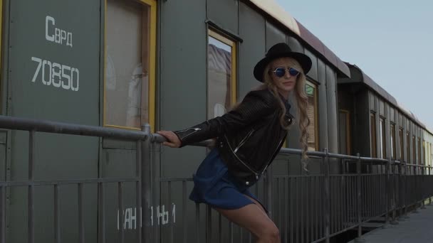 Mujer de moda apoyada en la cerca cerca del tren — Vídeos de Stock
