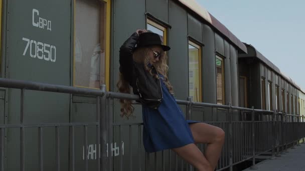 Mujer de moda apoyada en la cerca cerca del tren — Vídeos de Stock