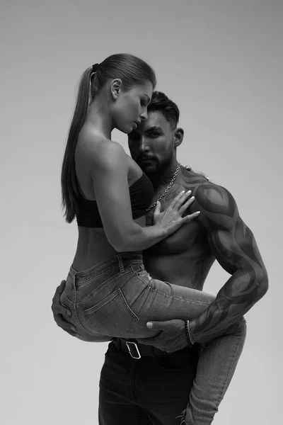 Black and white tattooed shirtless man and seductive topless woman looking away