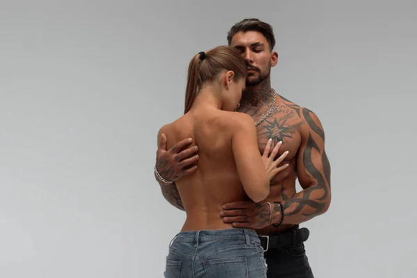 Muscular Tatuado Homem Abraçando Slim Topless Mulher Calcinha Fundo Cinza — Fotografia de Stock