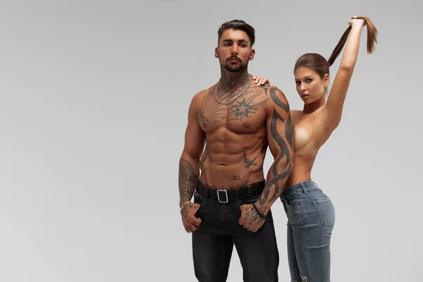 Muscular Tatuado Homem Abraçando Slim Topless Mulher Calcinha Fundo Cinza — Fotografia de Stock