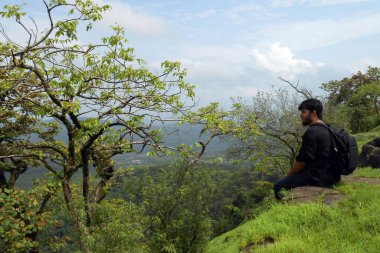 Adam dağın kenarında oturuyor.