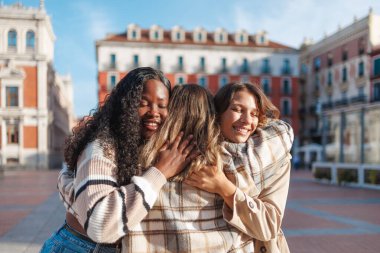 Çeşitli genç kadınlar kucaklaşır, sıcak bir kucaklaşma paylaşırlar.
