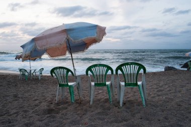Plaj şemsiyesi ve kötü havada sahilde plastik sandalyeler
