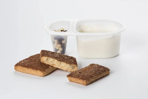 Jogurt s čokoládové kuličky. Dvojitý plastový pohár s bílým jogurtem a sladké skořicové sušenky. — Stock fotografie