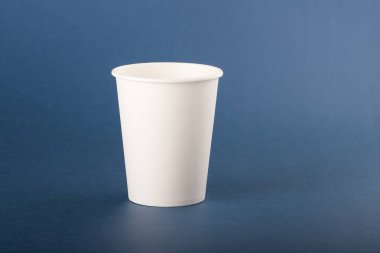 Mavi arka planda beyaz tek kullanımlık kağıt fincan