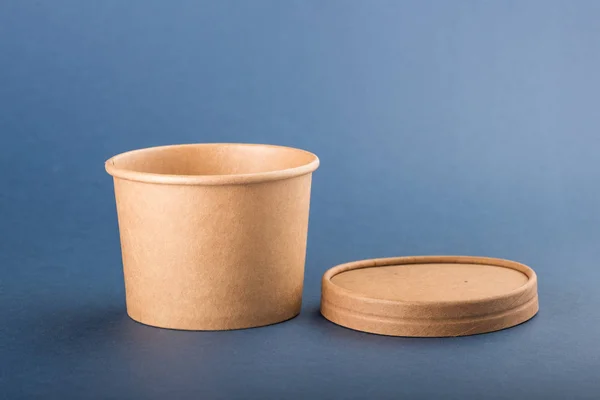 Disposable paper container with cap for soup on a blue background