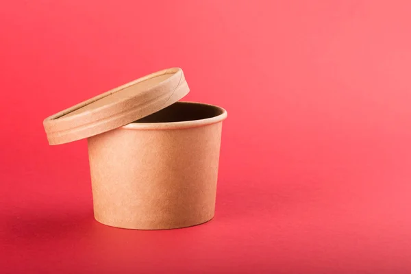 Disposable paper container with cap for soup on a red background
