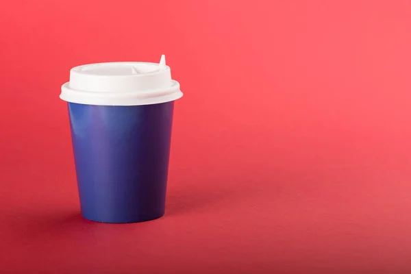 Blue disposable cup with white cap on a red background