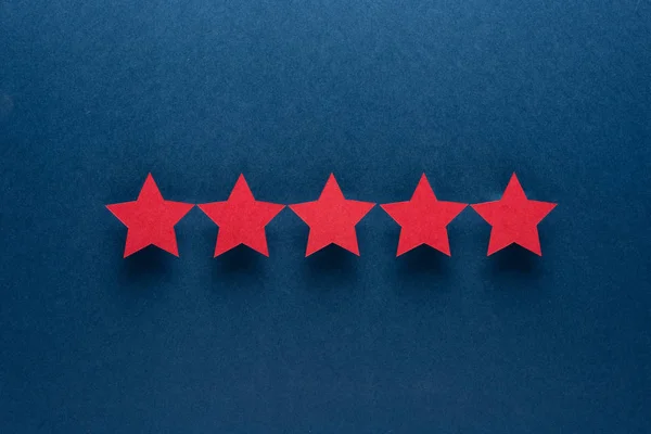 Concepto de retroalimentación. Cinco estrellas de aprobación de papel rojo sobre fondo azul . — Foto de Stock