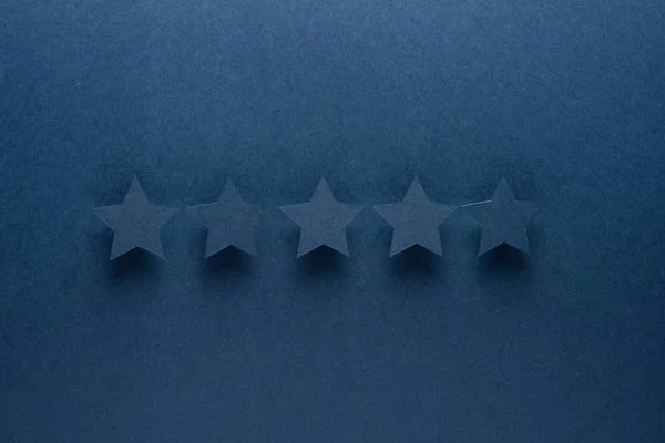 Feedback concept. Five blue paper stars of approval on a blue background.