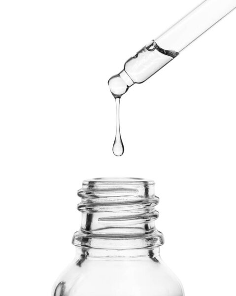 A drop falls into a glass bottle. Cosmetic oil dripping from a pipette on a white background.