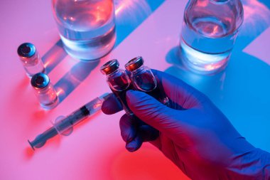 Doktor elinde aşılı bir şırınga tutuyor. Tıbbi eldiveni yakından verin. Tehlike kavramı ya da aşı ihtiyacı..