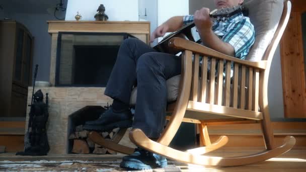 Человек Длинными Волосами Играть Гитаре Сидя Кресле Перед Камином — стоковое видео