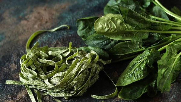 spinach fettuccine pasta with spinach leaves. vegetarian cuisine. uncooked pasta