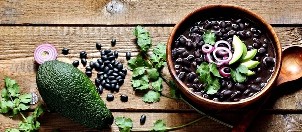 black bean soup or stew. Latin American or Mexican cuisine. stewed black beans served with avocado and red onion and cilantro. place for text.copy space