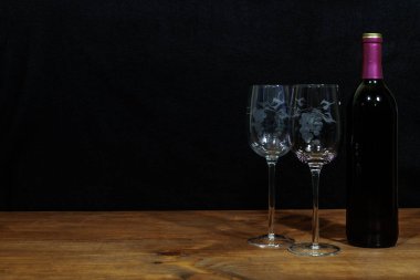 Güzel şarap, gözlük ve ahşap masa ve koyu arka plan üzerinde kırmızı şarap şişe kazınmış. Sevgililer, anneler günü, Paskalya, Noel, kavramları düğün