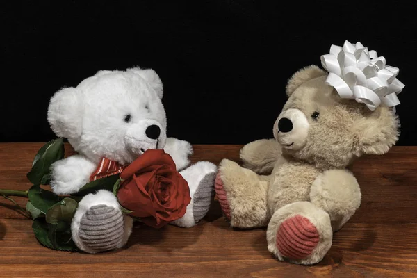 两个可爱可爱的泰迪熊与单一的红玫瑰和白色弓在木桌上在黑暗的背景 情人节 母亲节 复活节 圣诞节 婚礼概念 — 图库照片