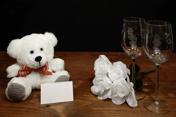 美丽的蚀刻酒杯与白玫瑰和白色泰迪熊和名称标签上的木桌和黑暗的背景 情人节 母亲节 复活节 圣诞节 婚礼概念 — 图库照片