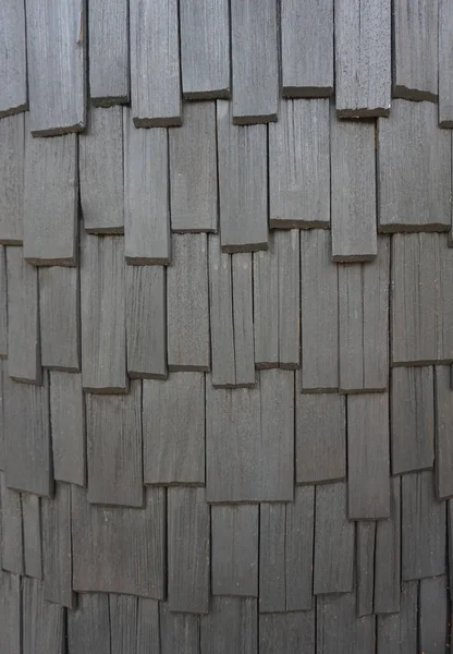 Rough bumpy wood shingle cladding, row of wooden material of small shingle wall facade.